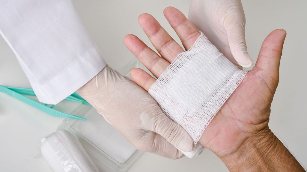 Doctor doing wound dressing care and bandaging patient's hand, H