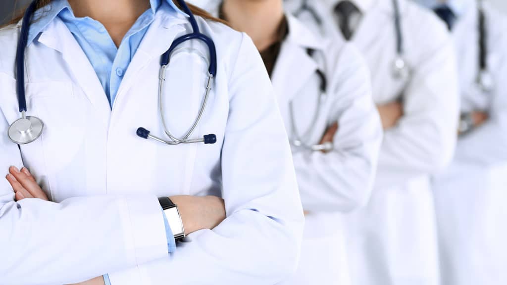 Group of modern doctors standing as a team with arms crossed in hospital office. Physicians ready to examine and help patients. Medical help, insurance in health care, best desease treatment and medicine concept