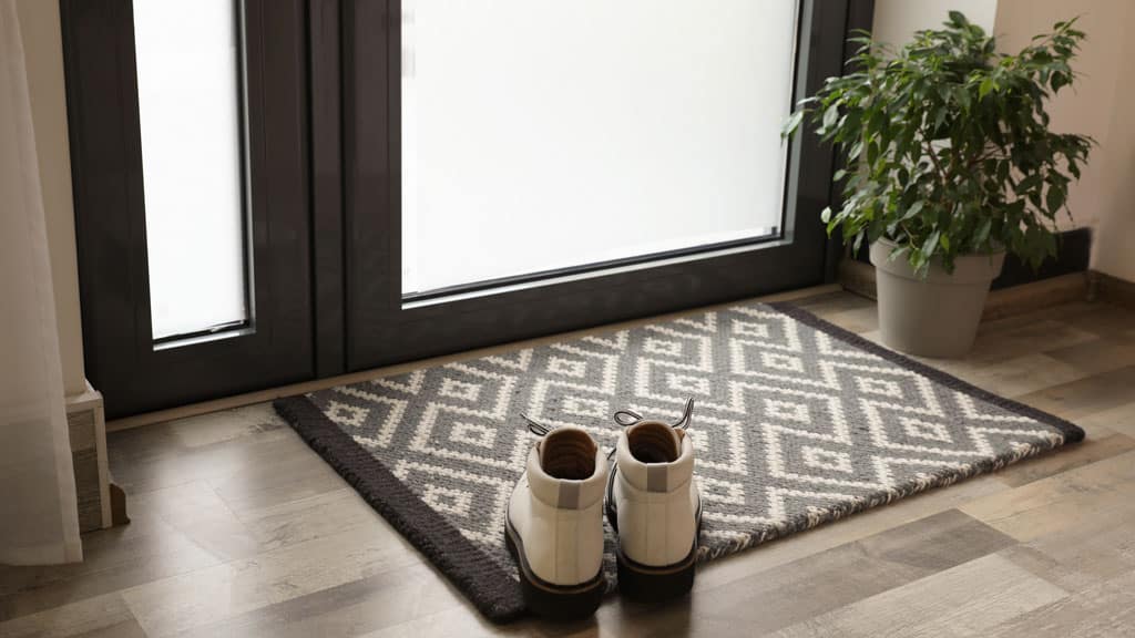 Stylish boots on door mat in hall