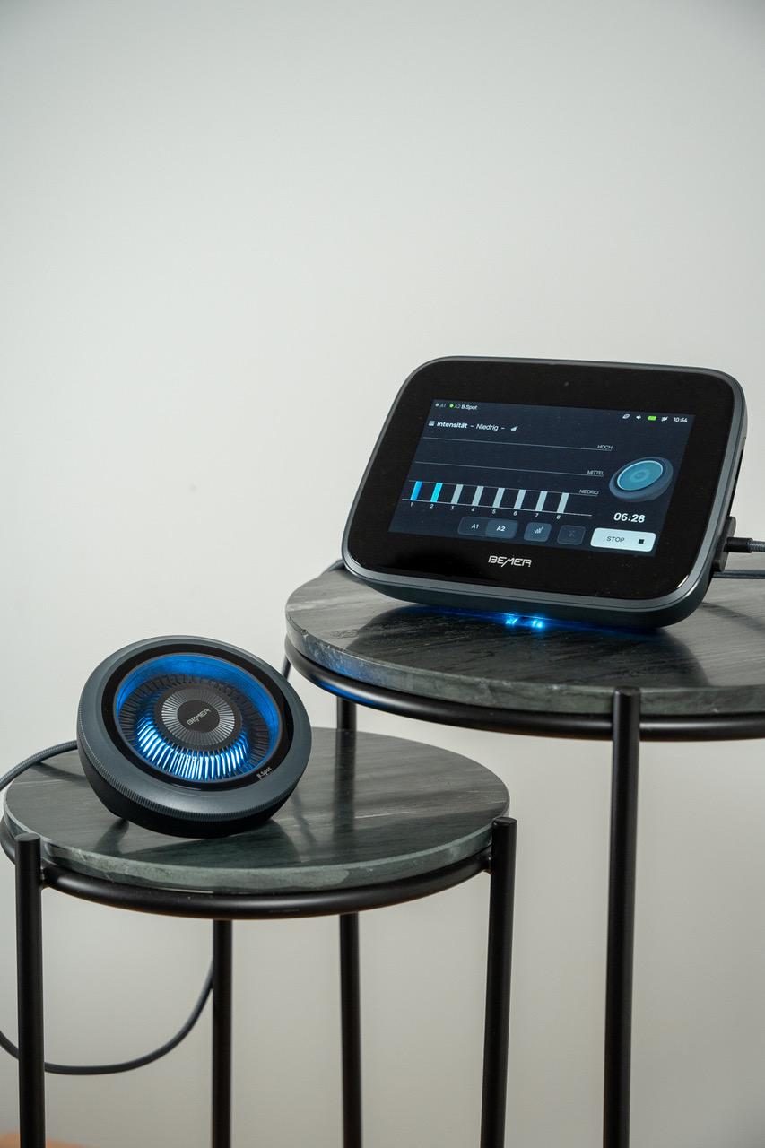 Ein schwarzes Audio-Interface mit beleuchtetem Regler und Bildschirm auf Tischen